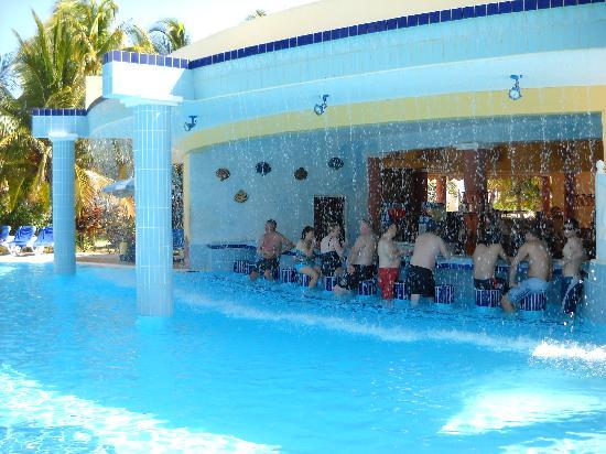 Personas sentadas en la terraza de un bar y mirando a una piscina